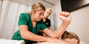 Massage therapist student massaging client's back