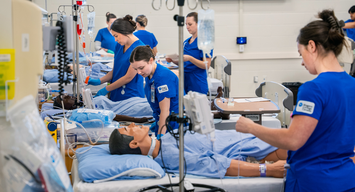 Nursing students in scrubs working in nursing lab with dummies