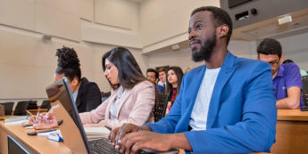 Diverse group of students listening and taking notes in lecture hall