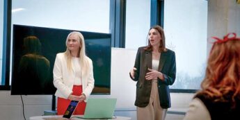 Two women giving a presentation in a boardroom.