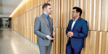 2 students in suits talk in hallway