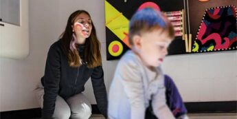 Student working with child on the ground of a classroom.