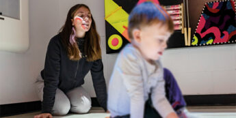 Student working with child on the ground of a classroom.