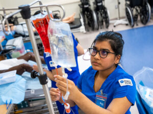 A nursing student refilling an IV bag in the practical nursing lab.