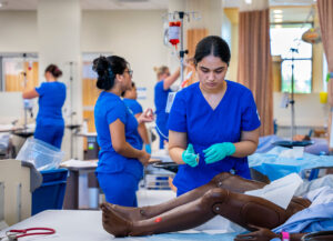 A nursing student practising on a hospital training manikin.