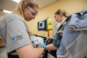 Two paramedic students in the paramedic lab practicing skills.