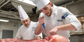 Chef and student working together in butchery or culinary training setting