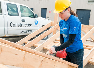 Girl wearing NC shirt and hard hat working on roof
