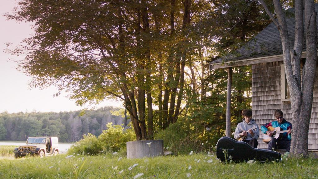 Two people sitting on a porch playing instruments