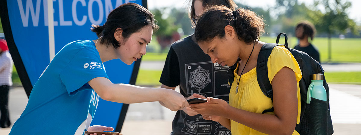 NC guide wearing NC t-shirt helps a student with directions on her phone