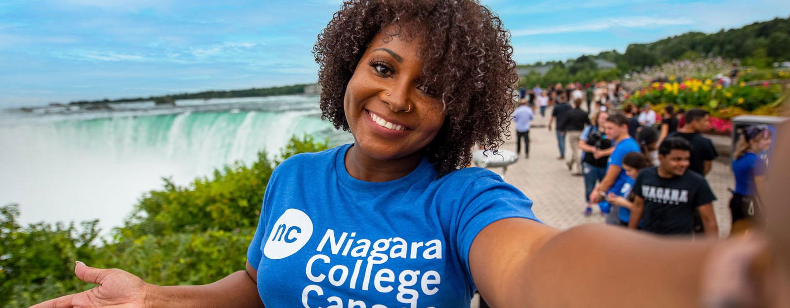 A student wearing NC gear gestures at Niagara Falls