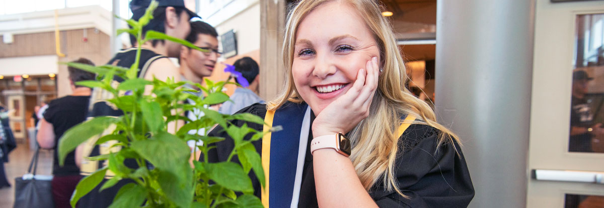 Female graduate in gown smiling with head on her hand