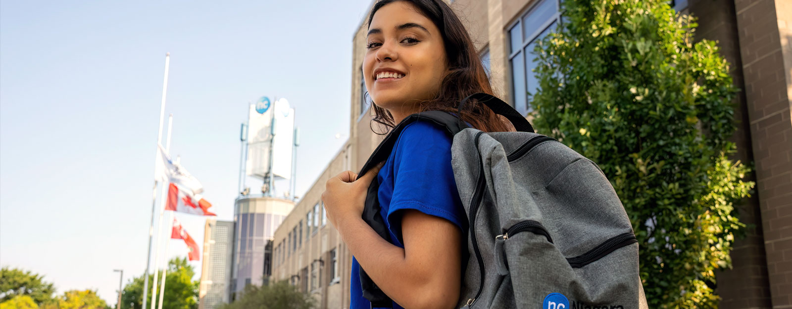 Female student with NC backpack in front of the NOTL campus