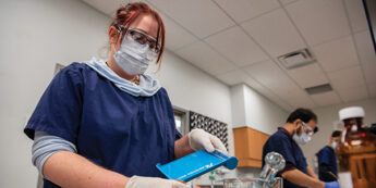 student with facemask on in lab organizing and sorting pills