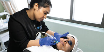 esthetician student working with skin equipment a client's face while laying down
