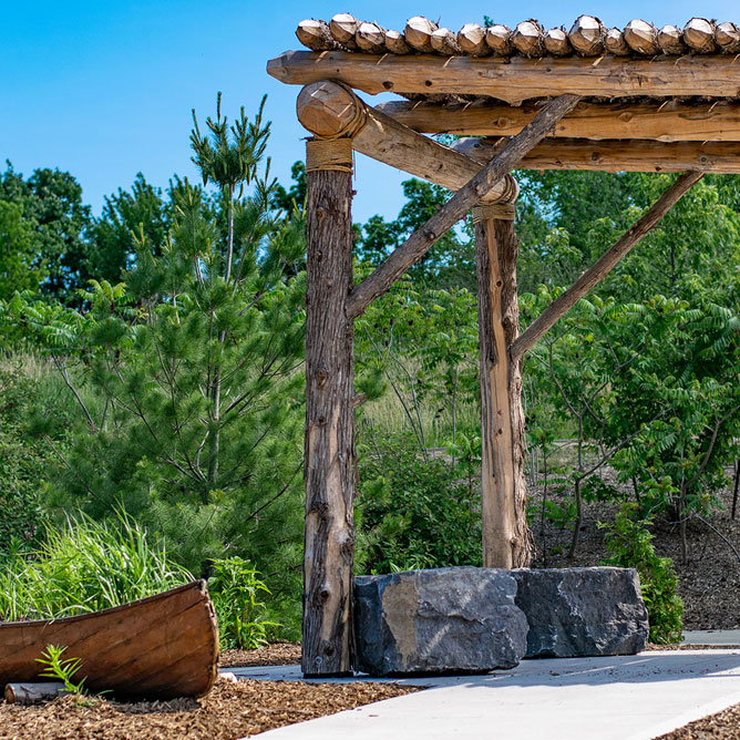 Wooden structure set above large stones surrounded by plants and trees