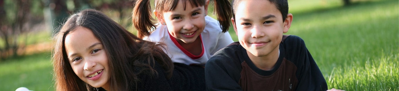 3 children laying in the grass.