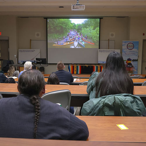 People in a classroom looking at projector screen.