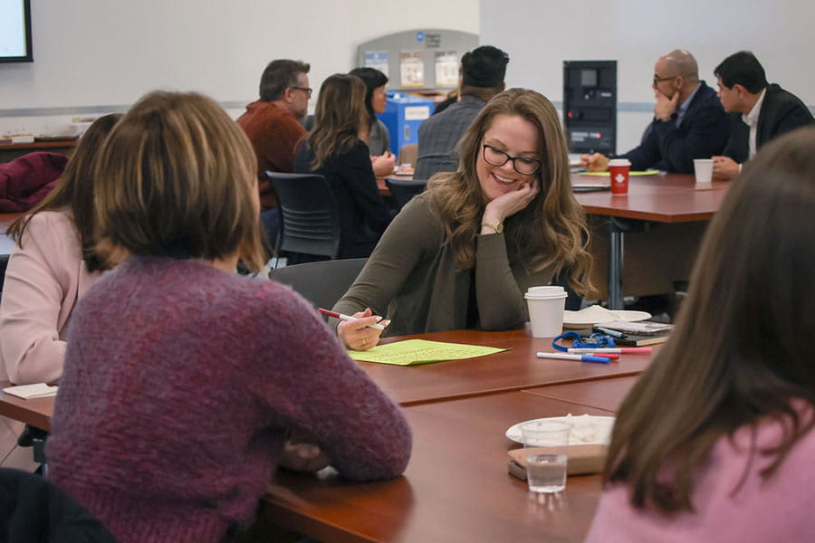 Paddling Together Seminar. Women talking around a table while one writes on paper.