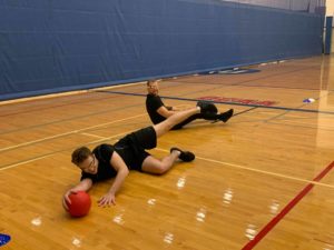 Fitness and health promotion students playing goalball while wearing goggles impairing their vision.