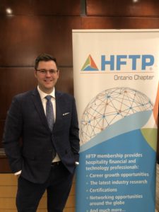 Andrew Buwalda next to a sign with the HFTP logo.
