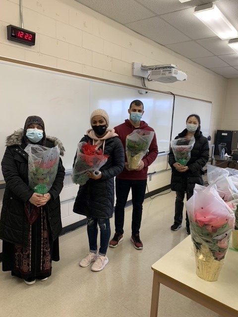 New Canadians at the Welland Heritage Council receive poinsettias donated by the Niagara College Teaching Greenhouse.