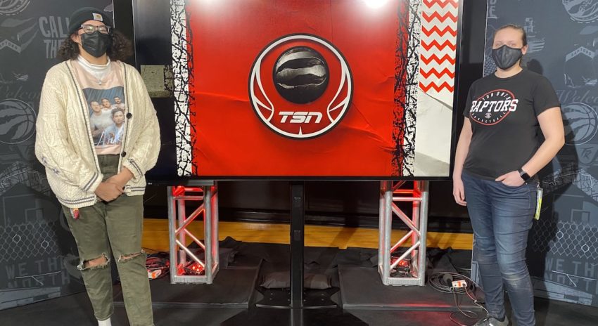 Two women stand next two a television screen with the TSN logo