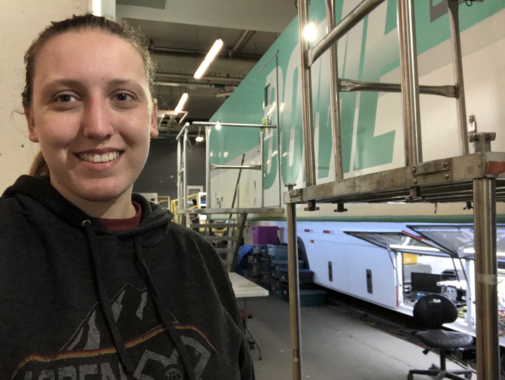 A woman takes a selfie outside a mobile production unit for broadcast.