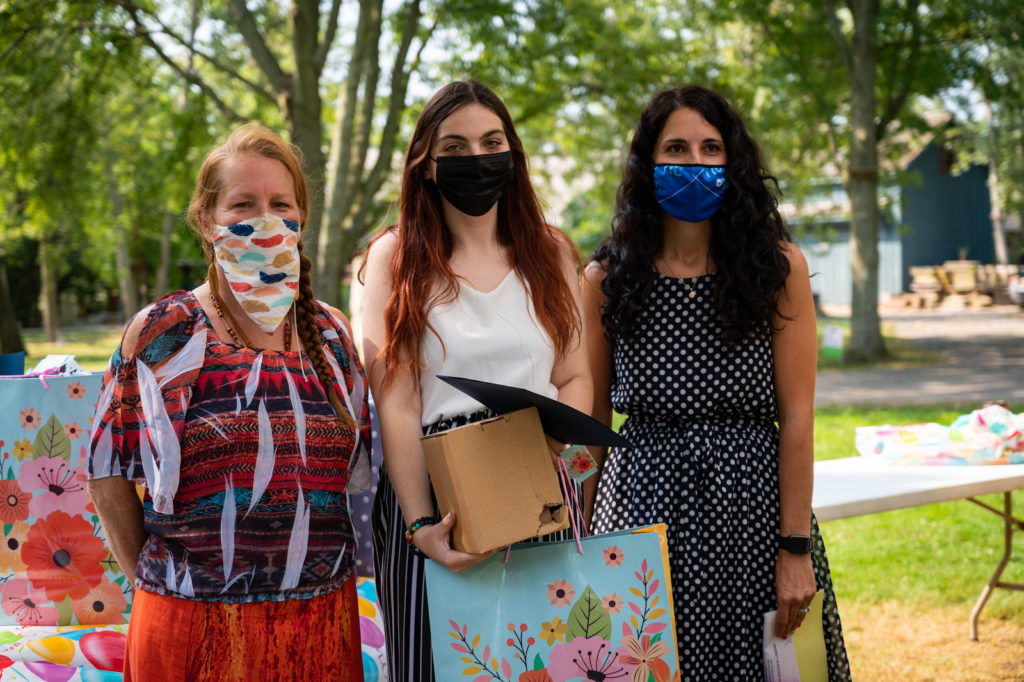 Three women stand together for a photo outside.