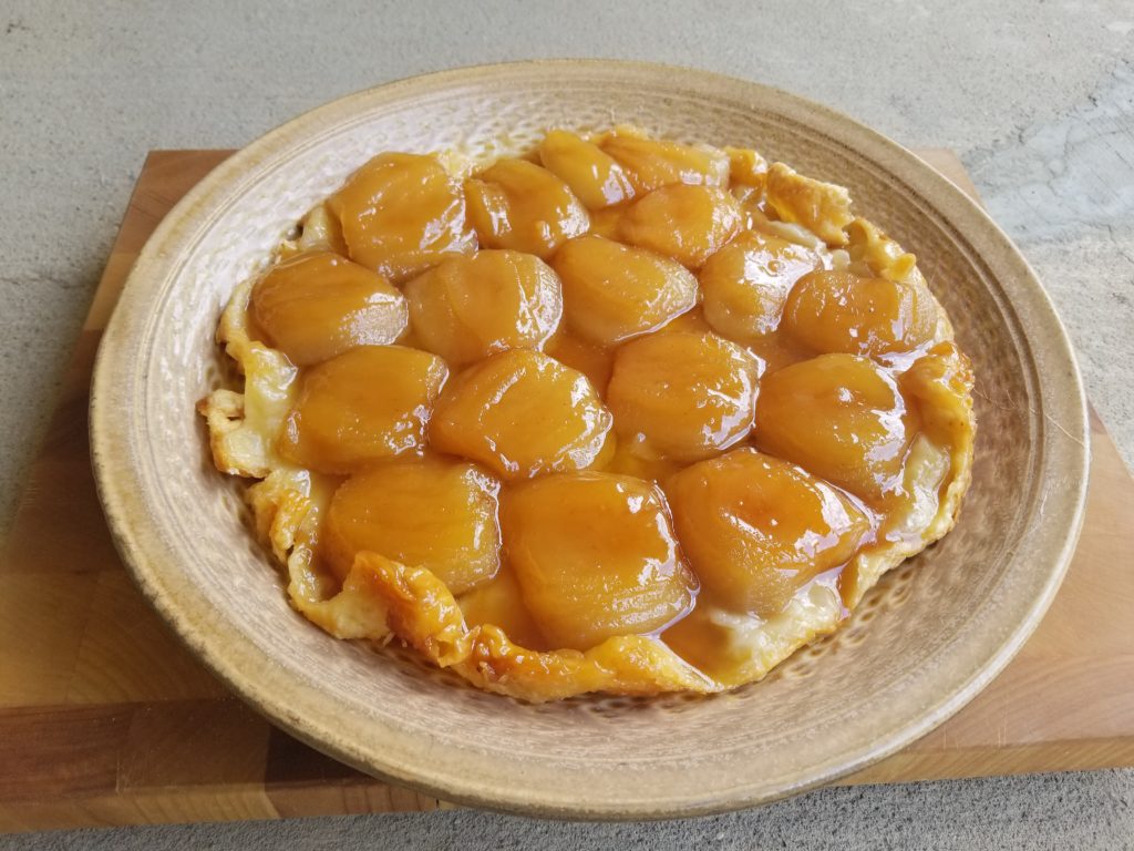 A closeup of a tarte tatin, a french apple cake that looks like an upside down cake with fruit on top.