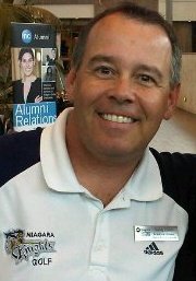 A headshot of a man in a polo shirt smiles at the camera