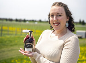 a woman with red hair wearing a white shirt holding a bottle of gin