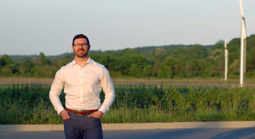 a mean wearing a white dress shirt stands in front of a green field