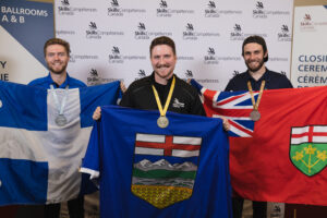 Three males stand with flags from their respective provinces