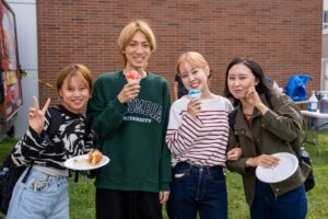 Three women and a man stand together eating ice cones