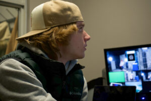 a student looks at a screen in a broadcasting control room