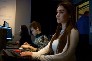 three students work in a broadcasting control room
