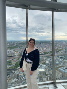 A girl standing in front of a window smiling at camera. 