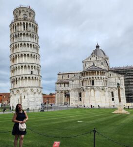 A girl standing in front of the Leaning Tower of Pisa