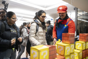 People, one in costume, overlooking table with coloured blocks.