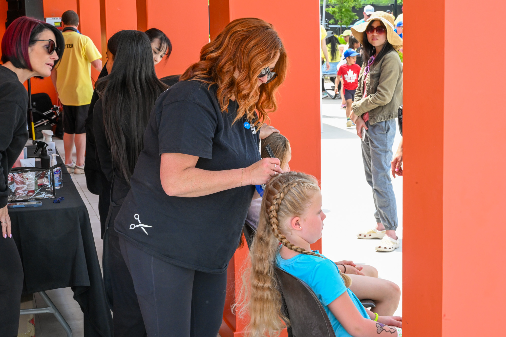 a woman styles a young girl's hair in braids