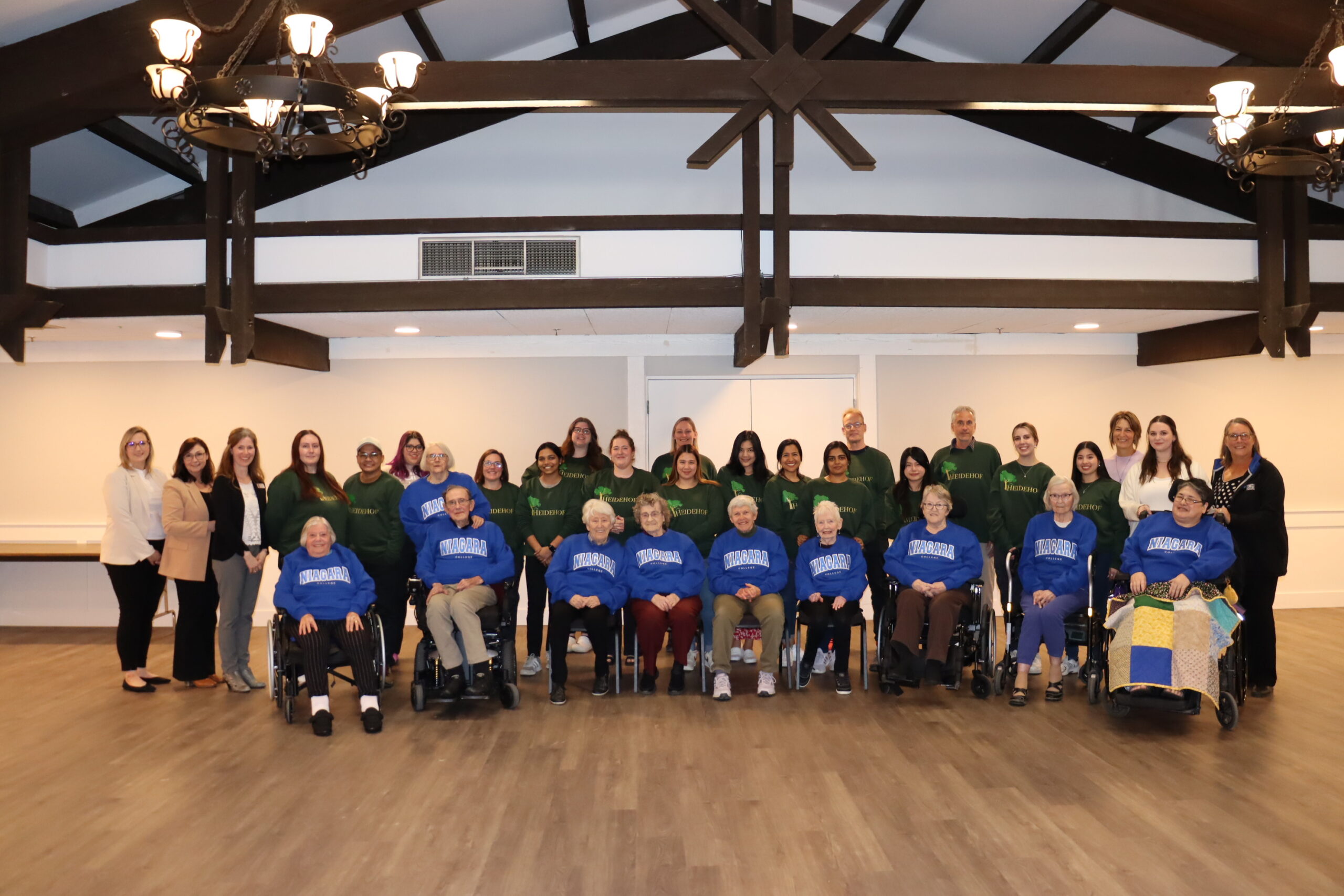 a group of people wearing sweatshirts pose for a photo inside a hall
