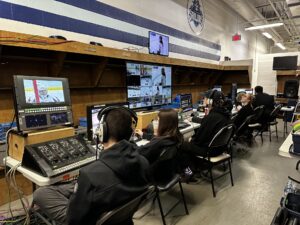 a line of people looking at monitors showing a hockey game
