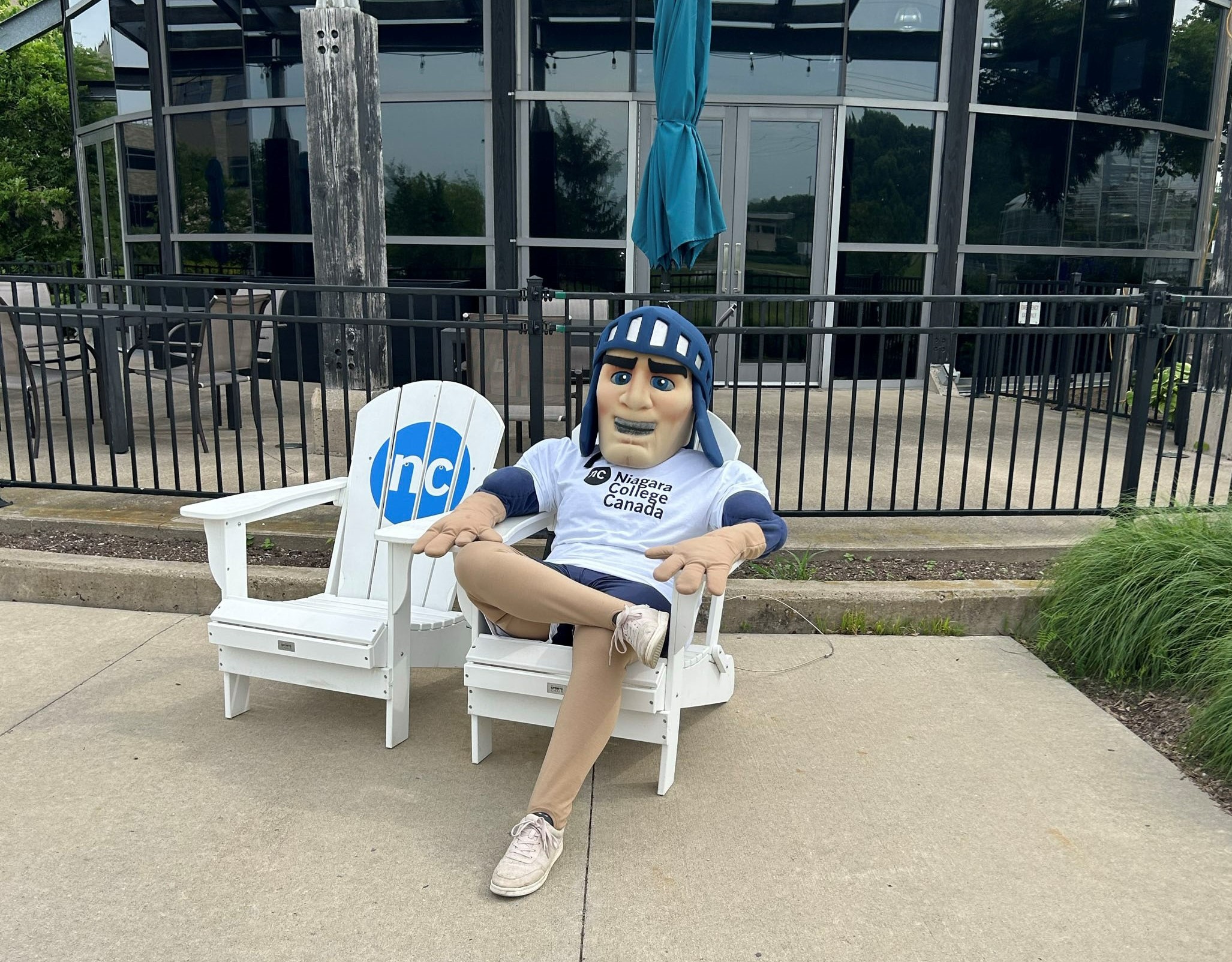 A Knight mascot sits in a white Muskoka chair