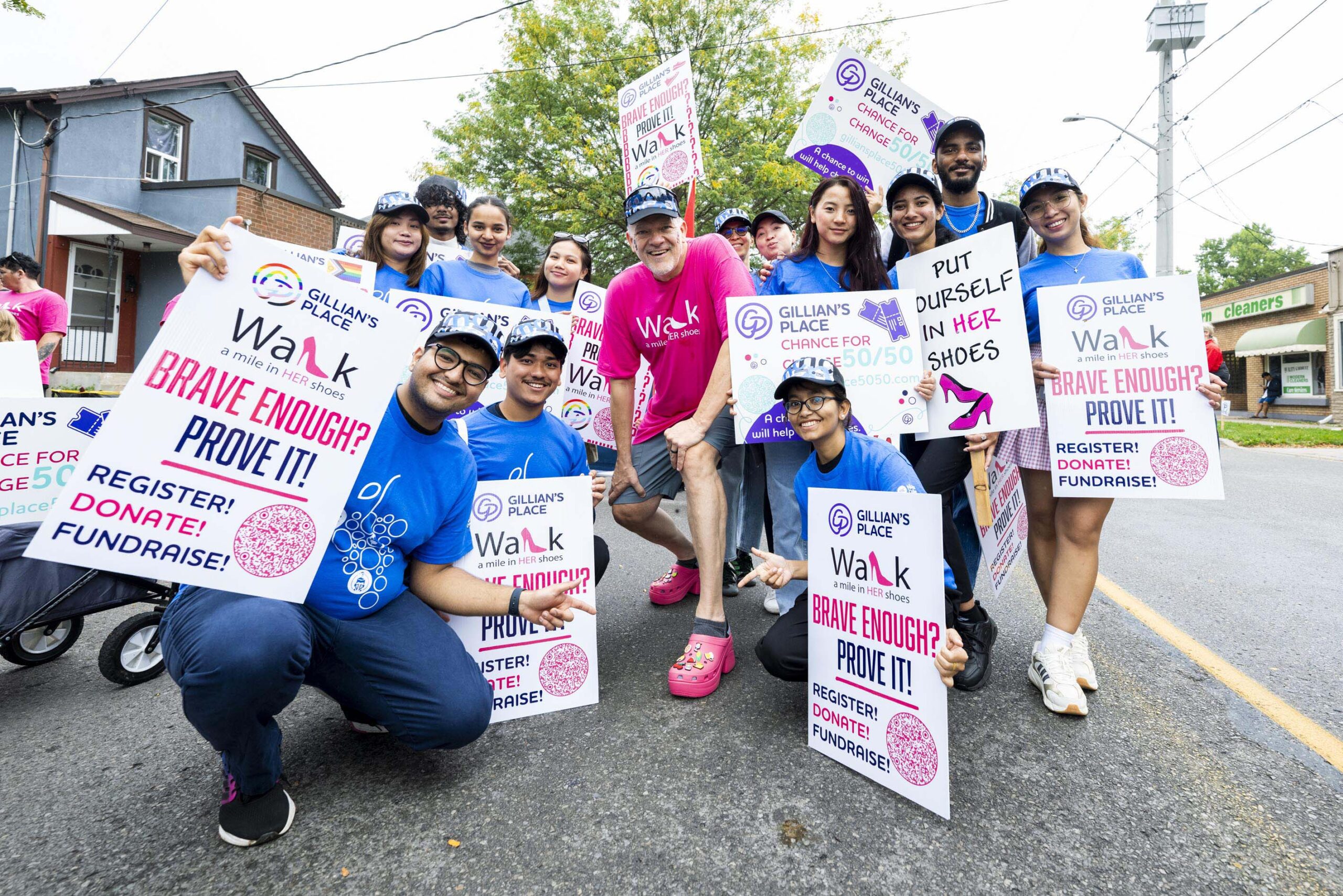 a group of people crouching on pavement holding signs 