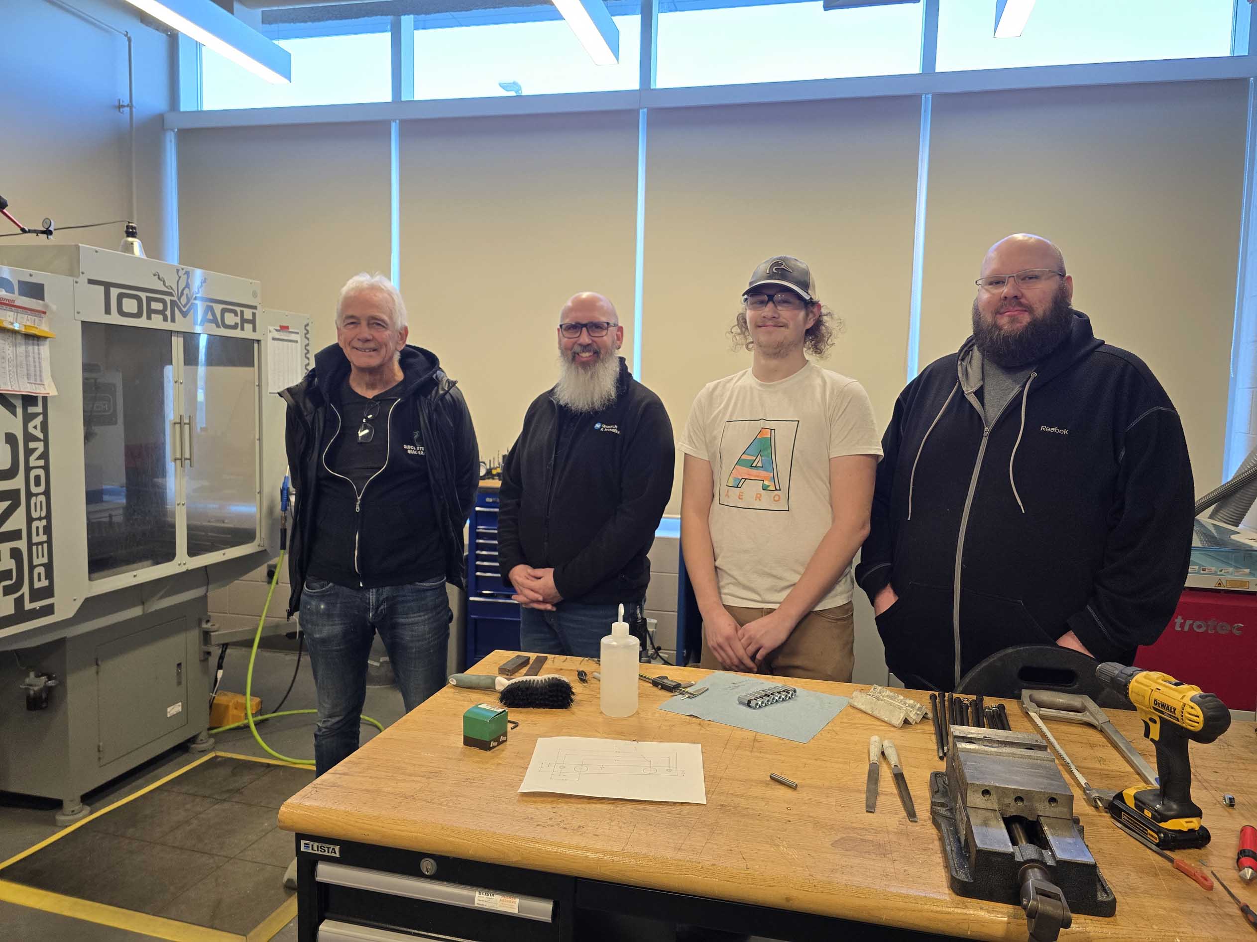 four men stand in a technology lab