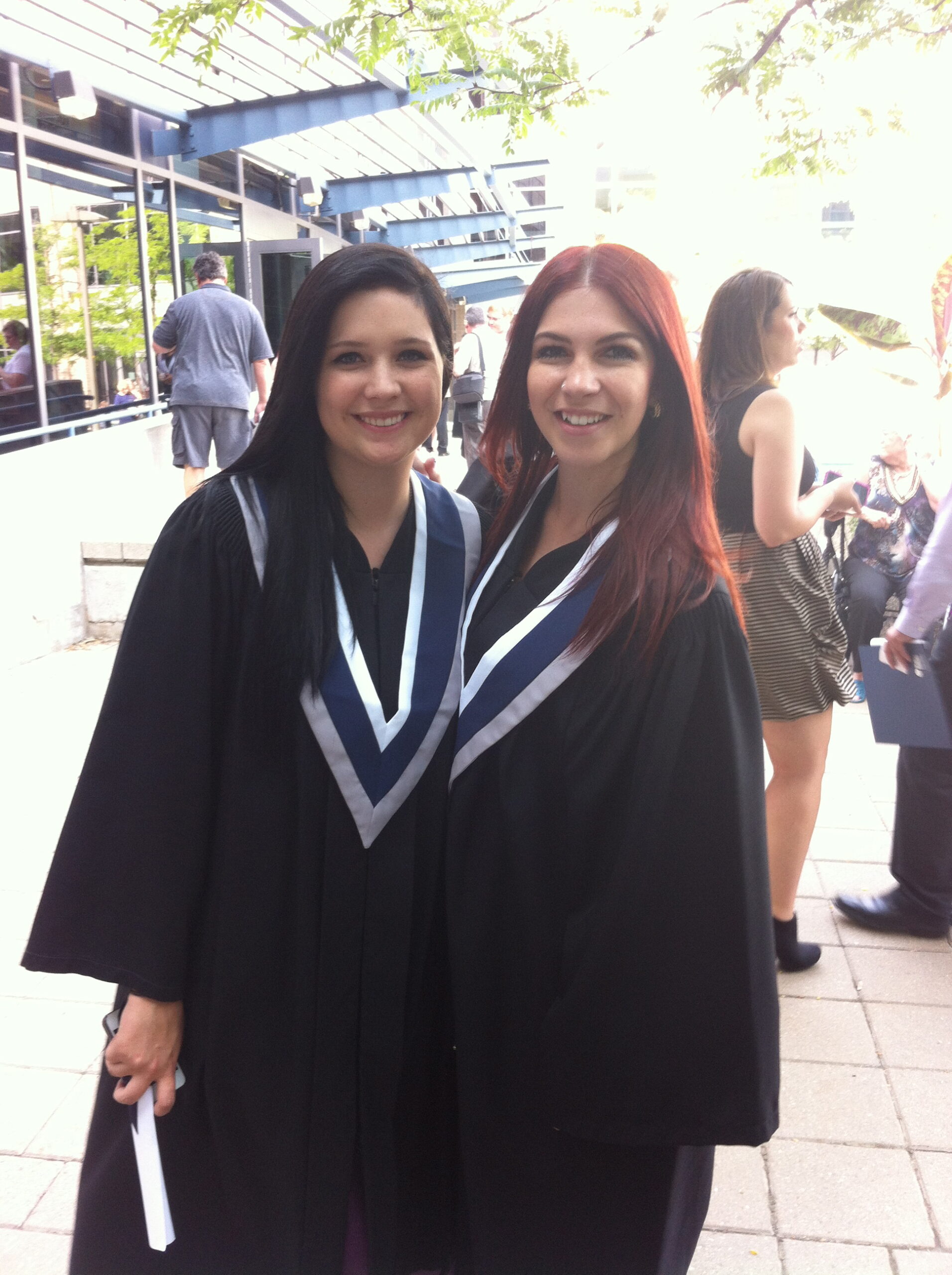 two young women wearing graduation robes pose for a photo