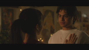 a screenshot of a movie scene featuring a young man looking at a young woman whose hand is on his chest