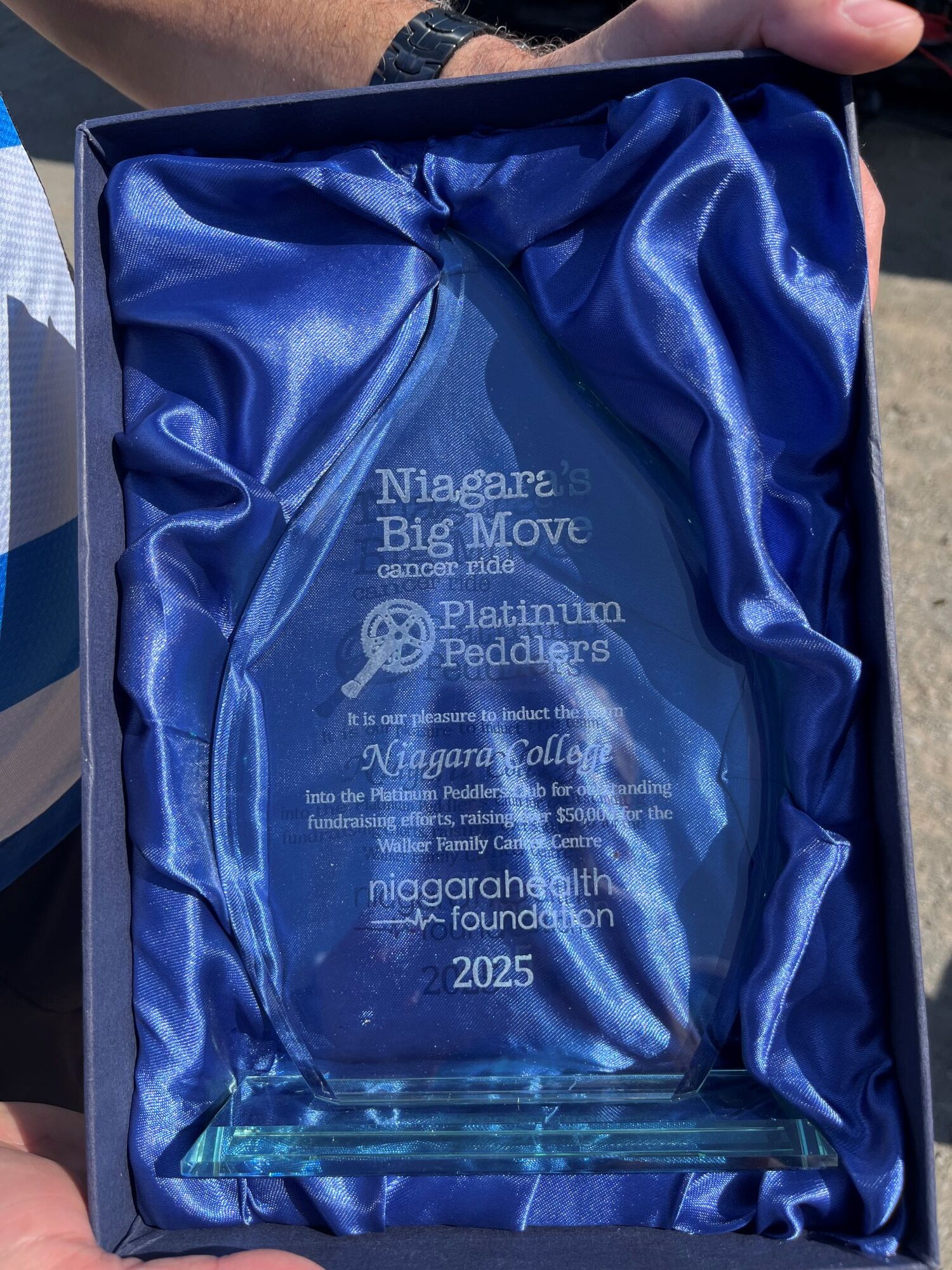 a photo of a clear glass award in a blue satin lined box