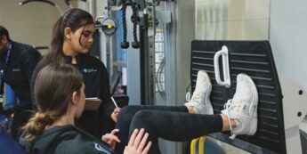 Female student teaching a client how to use an exercise machine in the gym.